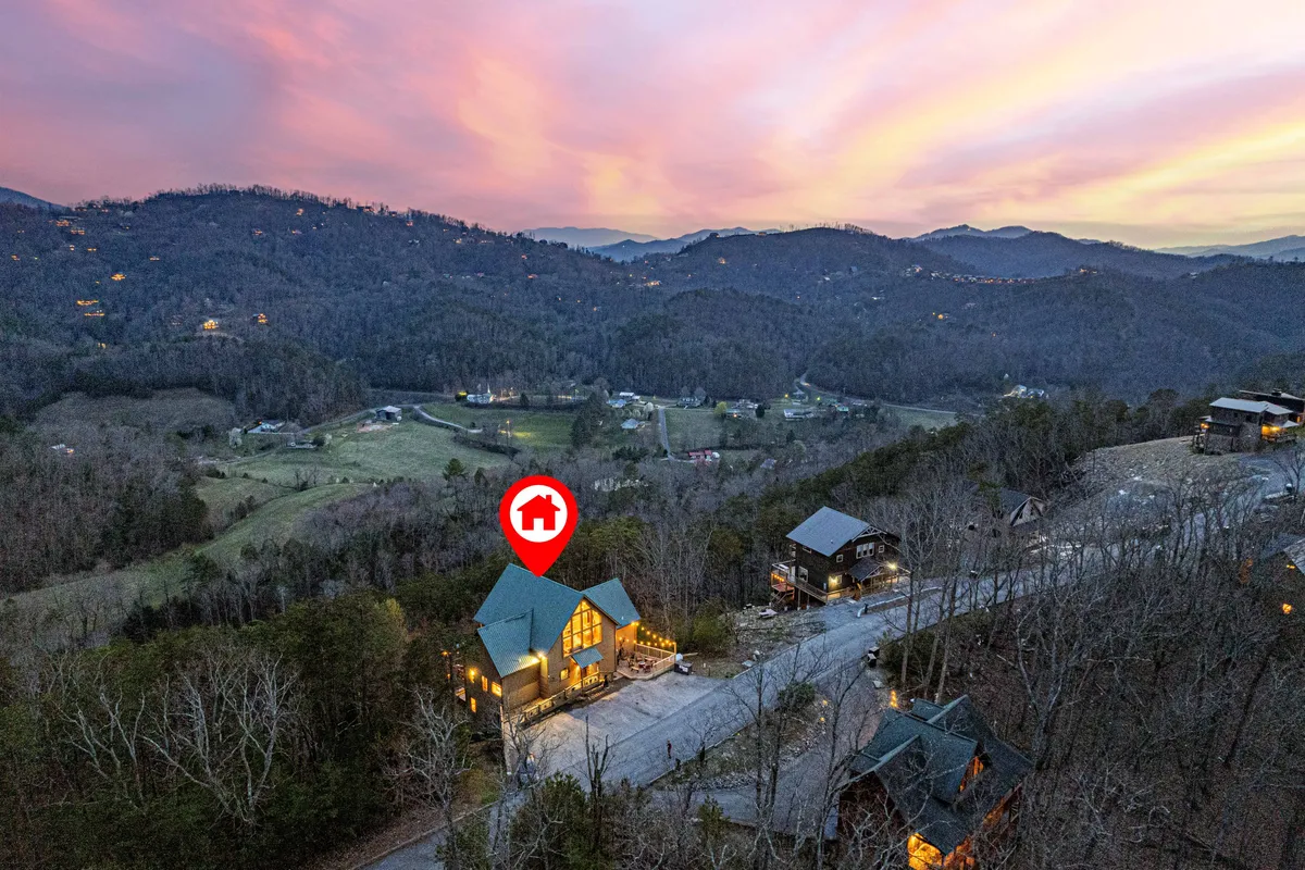 A wide-angle exterior shot of the house with large windows, a winding road leading towards distant mountains, and ample outdoor space. This setting hints at both the adventure waiting outdoors and the comfort that welcomes you home.