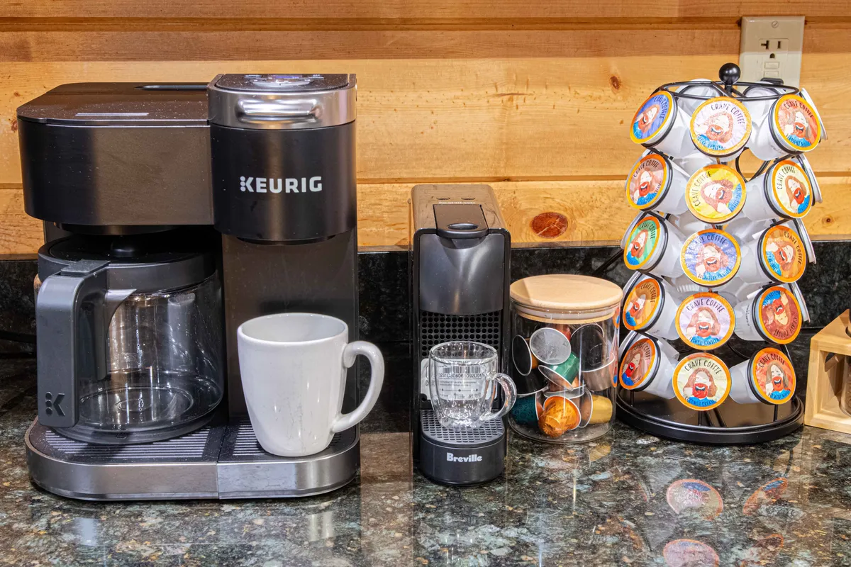 A dedicated coffee bar setup featuring a Keurig coffee maker, a high-end Breville espresso machine, and an organized coffee pod holder. The arrangement exudes warmth and convenience, perfect for morning routines and social coffee breaks.